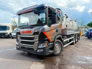 Vehicle livery for Blockfree Services on a grey Scania vacuum tanker featuring bold orange branding, illuminated company graphics and professional fleet vehicle signage. The design incorporates bright orange and grey branding graphics applied to the cab, illuminated company branding on the front grille and digital destination display, with a large white tanker mounted behind the cab.
