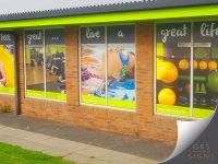Magna Vitae Trust for Leisure & Culture: Skegness Pool & Fitness Suite: Large window vinyl graphics. featuring a series of full-height photographic images across the glazed frontage. The graphics showcase activities including gym workouts, swimming, and fitness training, while bold white lettering across the tops of the windows spells out the slogan "feel great... live a great life". Bright lime green branding is incorporated throughout the design, including contrasting panels below the windows displaying the facility's website and logo. The vibrant imagery and colour scheme create an eye-catching exterior display that promotes health, fitness, and wellbeing while enhancing the building's visual identity.