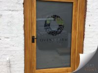 A frosted, cut-out vinyl on a double-glazing door with cut-out lettering and logo for Ovens Farm Vineyard. The combination of natural wood and elegant vineyard branding creates a premium and welcoming entrance display.