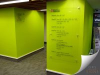 Two separate bespoke acrylic wayfinding signs for varying levels of a building, positioned prominently on bright green walls. Located at the University of Leicester.