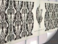 Large wall-mounted display panel featuring an ornate black, grey, and white wallpaper pattern. The design is shown in several vertical sample sections, with a stylised "V" logo and the word "VAPETROPOLIS" centred between the samples. The decorative pattern includes symmetrical floral and scroll motifs in a vintage style. The panel is mounted on a light-coloured wall.