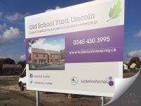 Dual-post external sign for Old School Yard, Lincoln. The white sign features purple branding and promotes “2 and 3 bedroom houses for shared ownership.” A computer-generated image of newly built homes is displayed on the left, while prominent contact information on the right includes the telephone number and website. Social media details for Waterloo Homes appear along the lower section, alongside the Help to Buy logo and Waterloo Homes branding.
