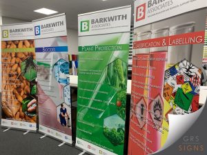 Set of four freestanding pull-up banner stands produced for Barkwith Associates displayed in an indoor exhibition setting.