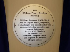 A close up of a circular sign which is engraved and paint-filled aluminium. The sign is for The William Penny Brookes Building.
