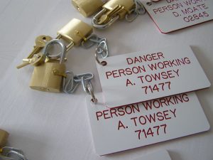 A close up of locks and keys attached to engraved danger boards (white with red engraved text)