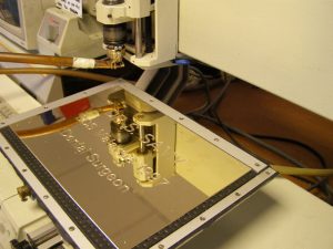An engraving machine in action, engraving a brass name plaque for a dental surgeon