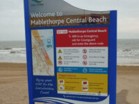 A modular sign outside at Mablethorpe Central Beach. It features safety warnings, information about lifeguard services, emergency information - and a map of the area.