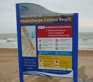 A modular sign outside at Mablethorpe Central Beach. It features safety warnings, information about lifeguard services, emergency information - and a map of the area.