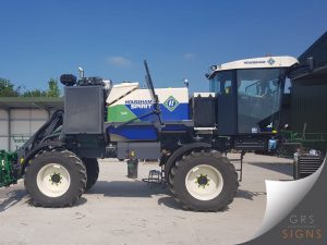 Side view of a Househam Predator self-propelled agricultural sprayer featuring the company's distinctive blue, white, and green livery. Large Househam Predator branding is displayed prominently on the side-mounted tank, with angled green graphics incorporating the Househam logo.