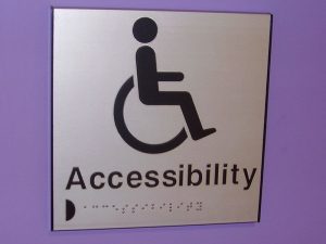A close up of a tactile and braille aluminium accessibility toilet sign.