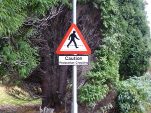 Lamppost mounted caution sign to warn of pedestrians crossing.