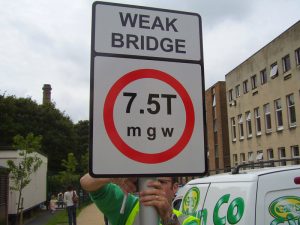 Post-mounted aluminium traffic sign, warning of a weak bridge