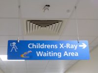 A hanging wayfinding sign within the NHS to show directions for the childrens x-ray waiting area.