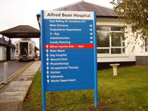 NHS directional signage at Alfred Bean Hospital, East Riding of Yorkshire. Dual-post installation, predominantly blue with white text and a bold red to highlight a minor injuries unit.